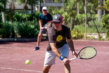 Load image into Gallery viewer, A man wearing Hit Happy Tennis Wristbands while playing tennis on the court
