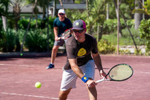 Load image into Gallery viewer, A man wearing Hit Happy Tennis Wristbands while playing tennis on the court