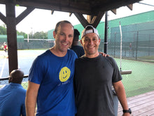 Load image into Gallery viewer, A man wearing the blue Hit Happy Tennis- Men's Next Level Triblend T-Shirt with a friend